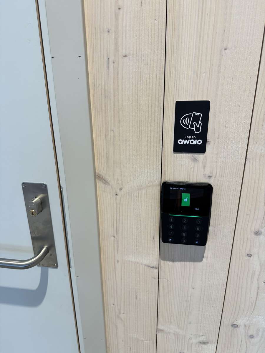 An Awaio TapCard reader mounted on an office door, ready for the user to tap their phone